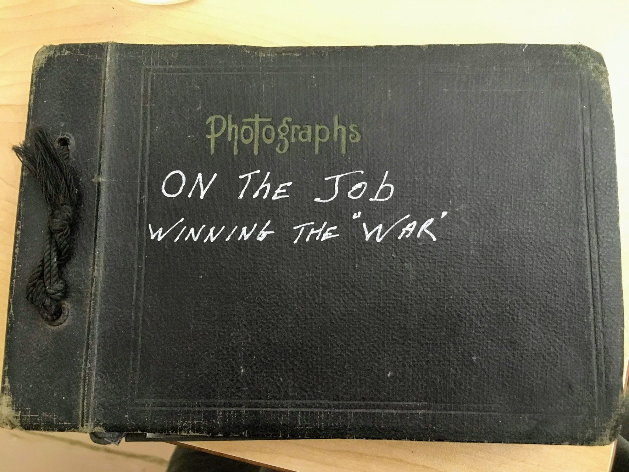 An old photo album that says, 'On the job, winning the "War"' with War in inverted commas