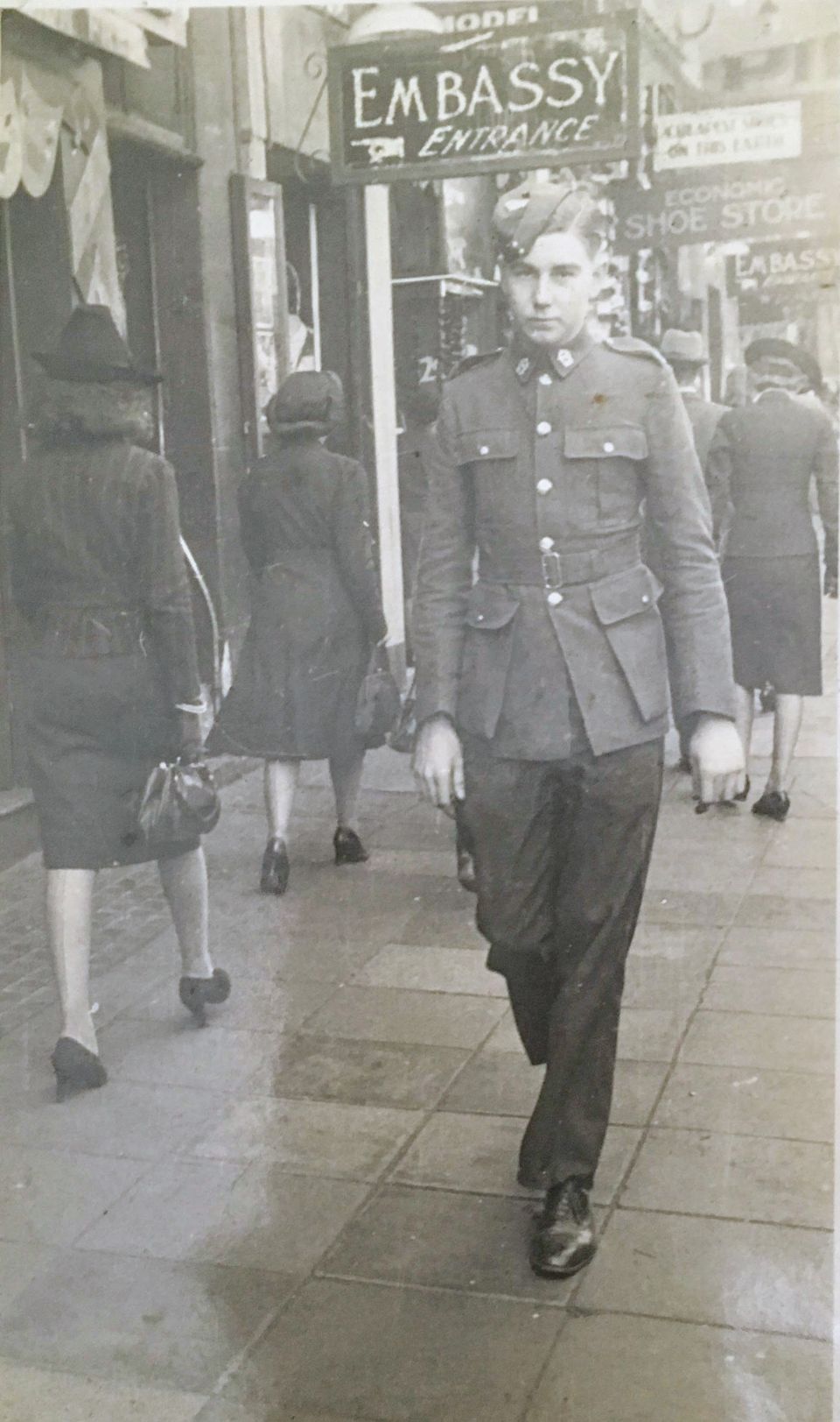 A photograph of a young soldier walking down a busy city street